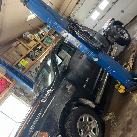 Véhicule surélevé sur un pont élévateur pour une inspection du dessous de caisse en atelier.